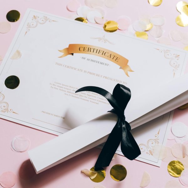 Elegant certificate of achievement on a pink surface with confetti. Perfect for celebrations and achievements.